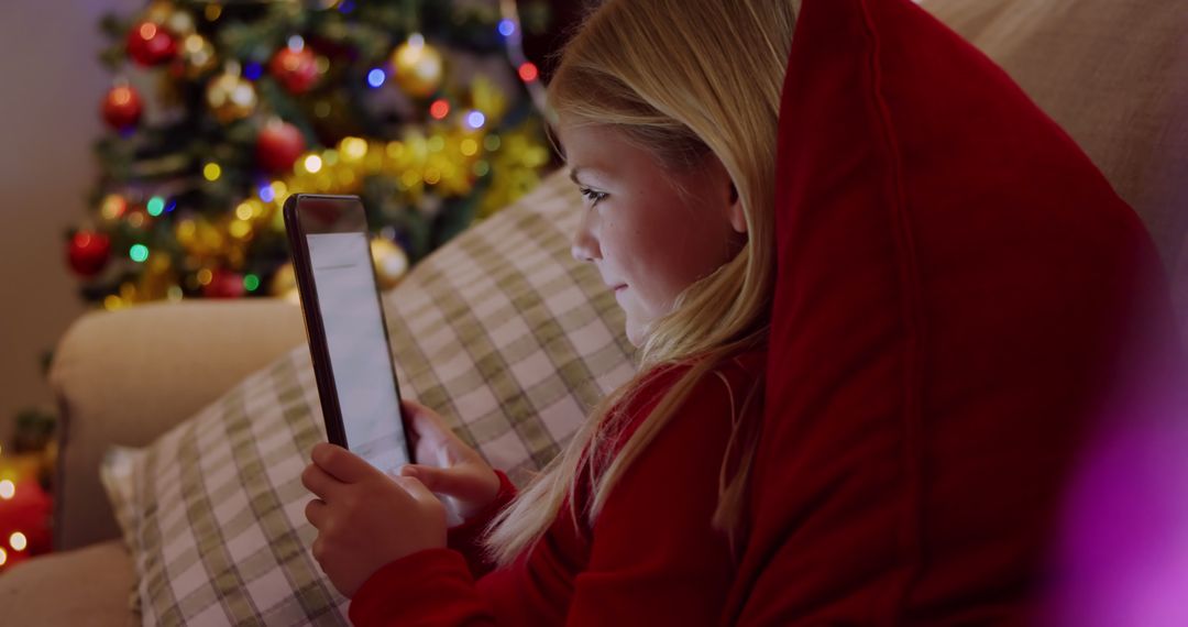 Child Engaged with Tablet by Christmas Tree - Free Images, Stock Photos and Pictures on Pikwizard.com