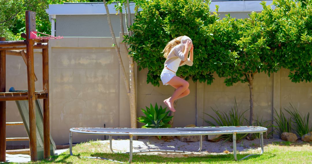 Girl Jumping on Trampoline in Sunny Backyard - Free Images, Stock Photos and Pictures on Pikwizard.com