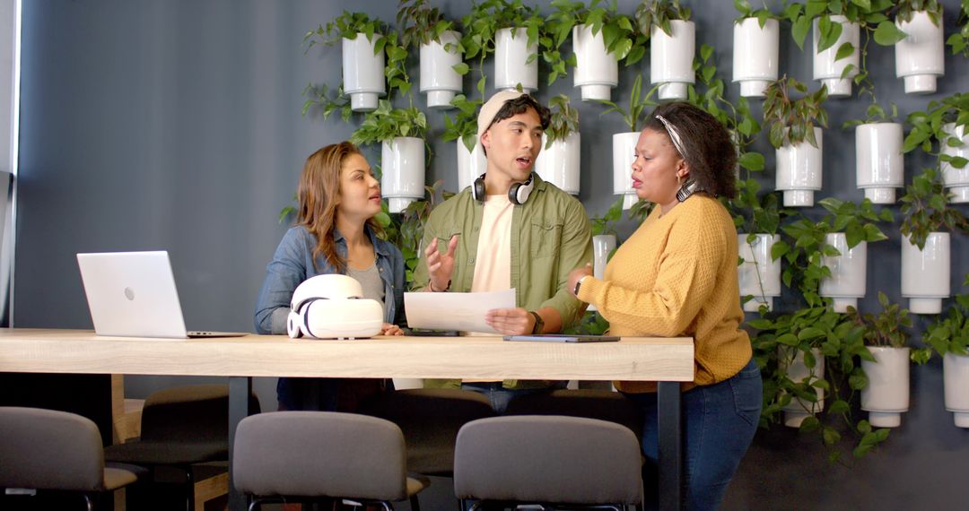 Diverse Team Collaborating Around High Table in Modern Office with Vertical Plant Wall