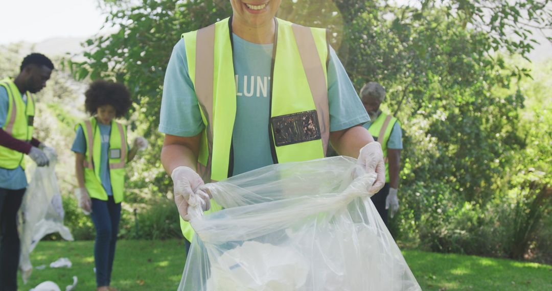 Midsection of smiling biracial woman holding refuse sack, clearing up trash outdoors with family - Free Images, Stock Photos and Pictures on Pikwizard.com