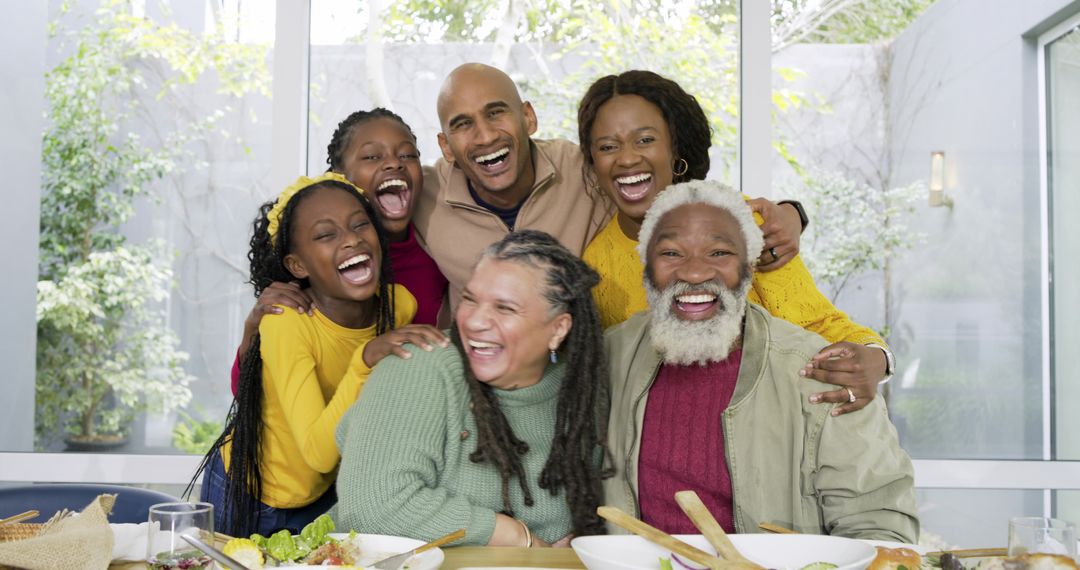 Multigenerational family laughing and sharing salad at sunlit dining table