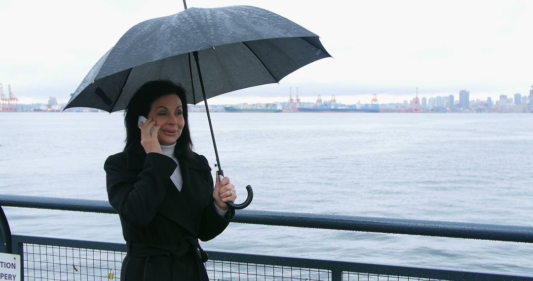 Businesswoman Talking on Cellphone Under Rainy Sky Near Harbor - Free Images, Stock Photos and Pictures on Pikwizard.com