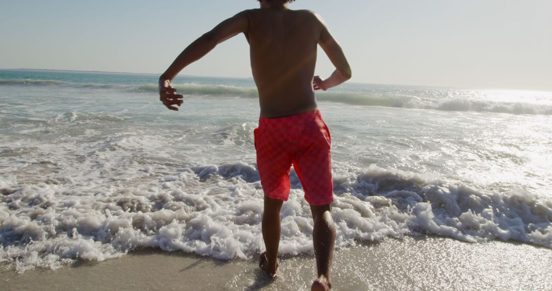 Man Running into Ocean Waves at Sunny Beach - Free Images, Stock Photos and Pictures on Pikwizard.com