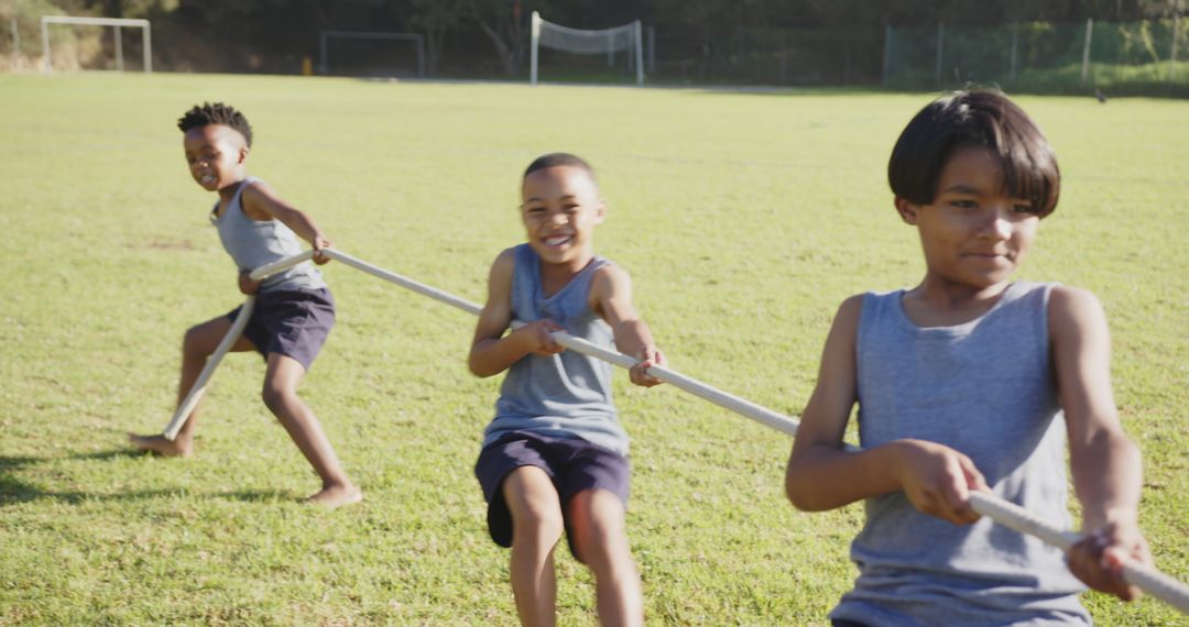 Smiling Boys Enjoying Tug-of-War Games on Sunny Field