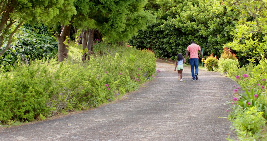 Father and Daughter Strolling Garden Path Under Lush Trees