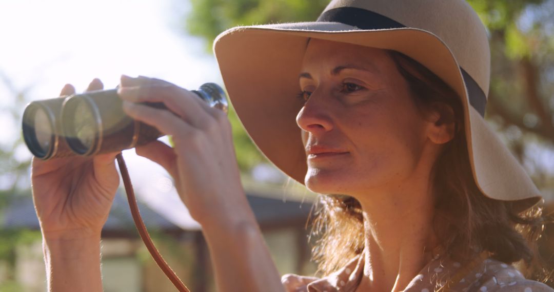 Woman in Wide-Brimmed Hat Using Binoculars in Sunlit Garden - Free Images, Stock Photos and Pictures on Pikwizard.com