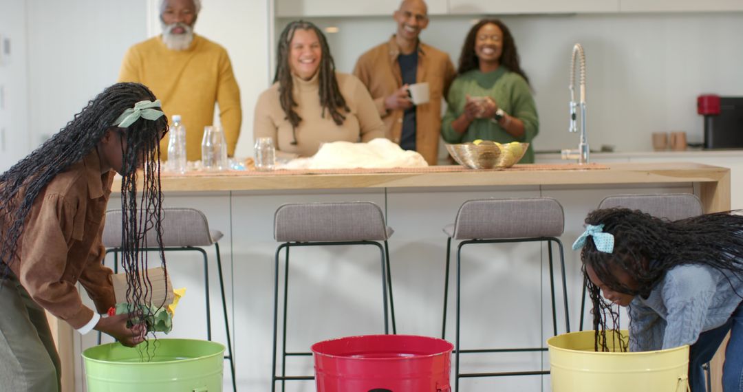 Multigenerational family laughing while children playing bucket game at kitchen island