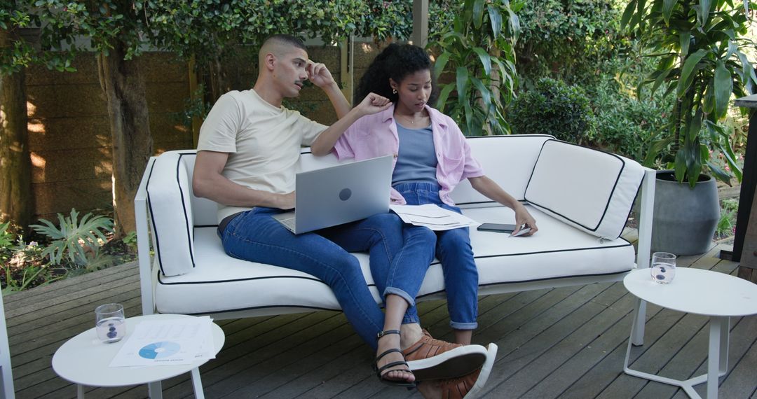 Diverse Couple Internet Browsing While Relaxing on Comfortable Garden Sofa