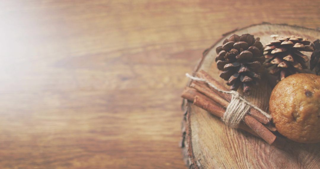 Evoking cozy autumn mood with pine cones, cinnamon sticks and muffin on wood slice