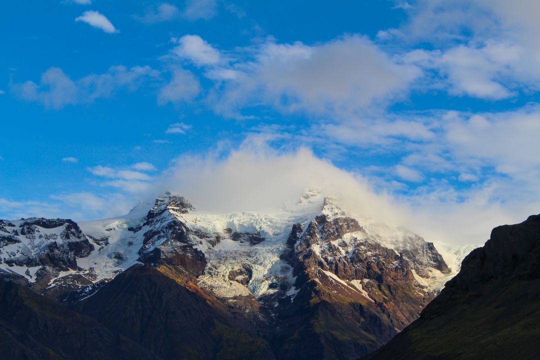 Snow-capped mountain peak against blue sky with clouds - Free Images, Stock Photos and Pictures on Pikwizard.com