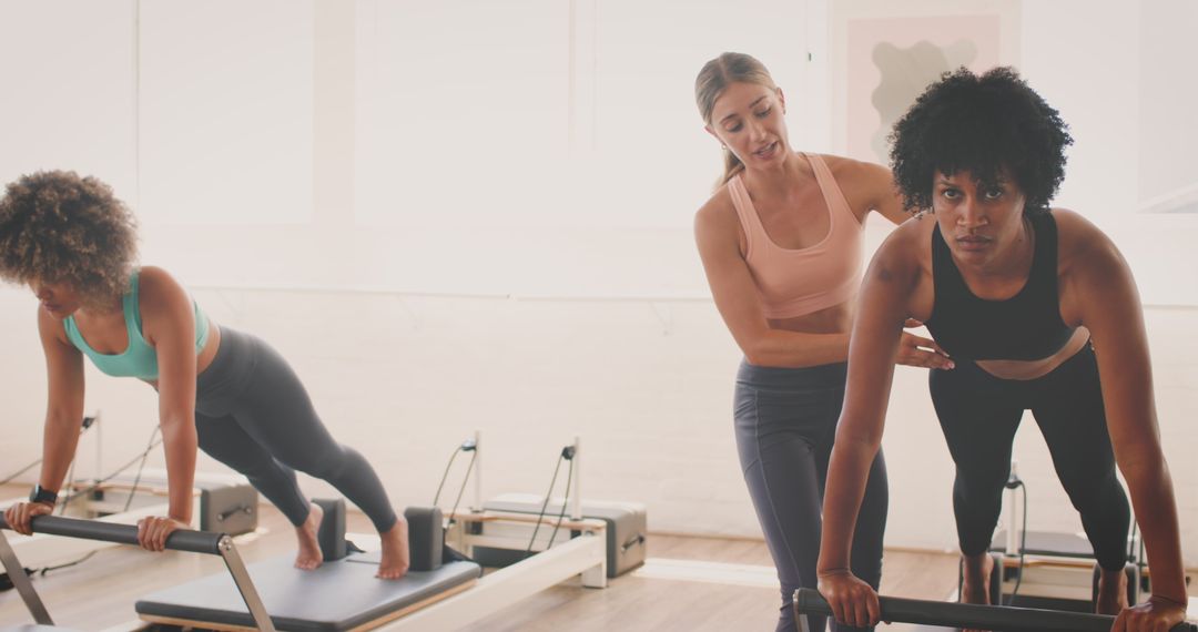 Fitness Instructor Assisting Women Exercising on Reformers