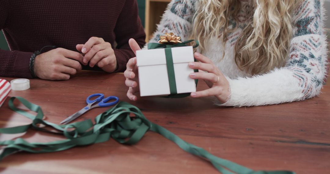 Couple Wrapping Christmas Gift Together on Wooden Table - Free Images, Stock Photos and Pictures on Pikwizard.com