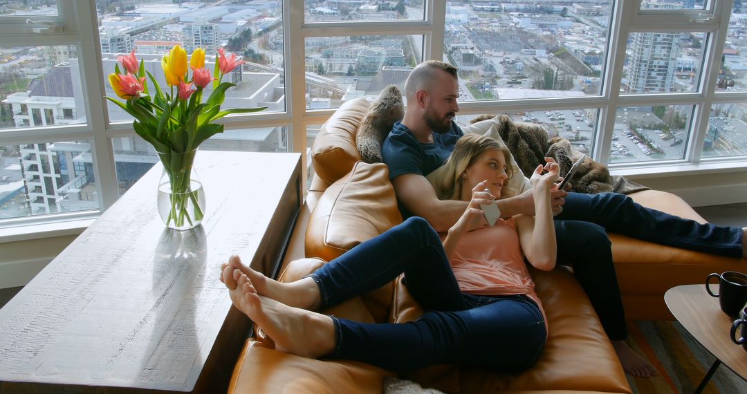 Relaxed Couple Hanging Out on Modern Apartment Sofa with City View - Free Images, Stock Photos and Pictures on Pikwizard.com