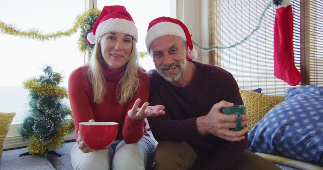 Smiling Couple Enjoying Hot Beverages by Christmas Decorations - Free Images, Stock Photos and Pictures on Pikwizard.com