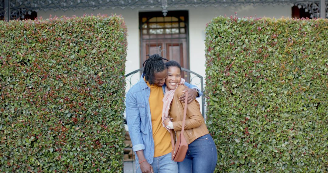 Happy Couple Hugging Outside Their Home Block with Green Hedges - Free Images, Stock Photos and Pictures on Pikwizard.com