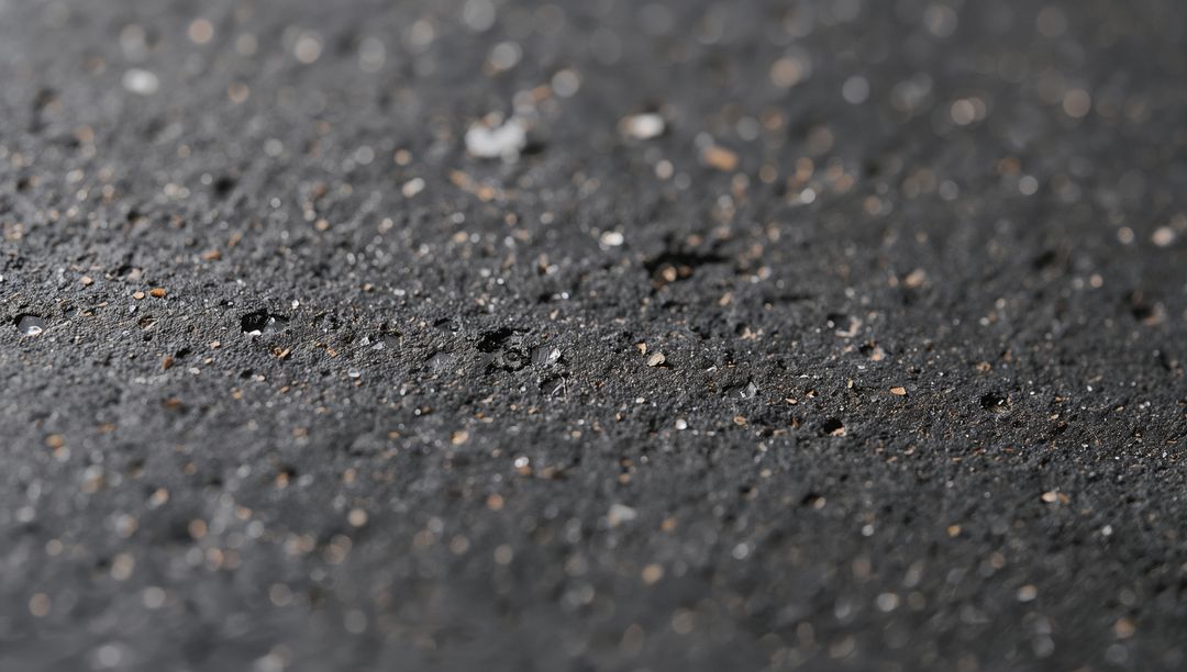 Rain-Kissed Asphalt Macro Texture with Gravel, Droplets, Cracks and Wet Bokeh Closeup