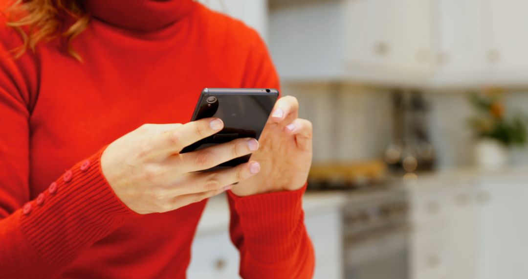 Person Wearing Red Sweater Using Smartphone in Modern Kitchen - Free Images, Stock Photos and Pictures on Pikwizard.com