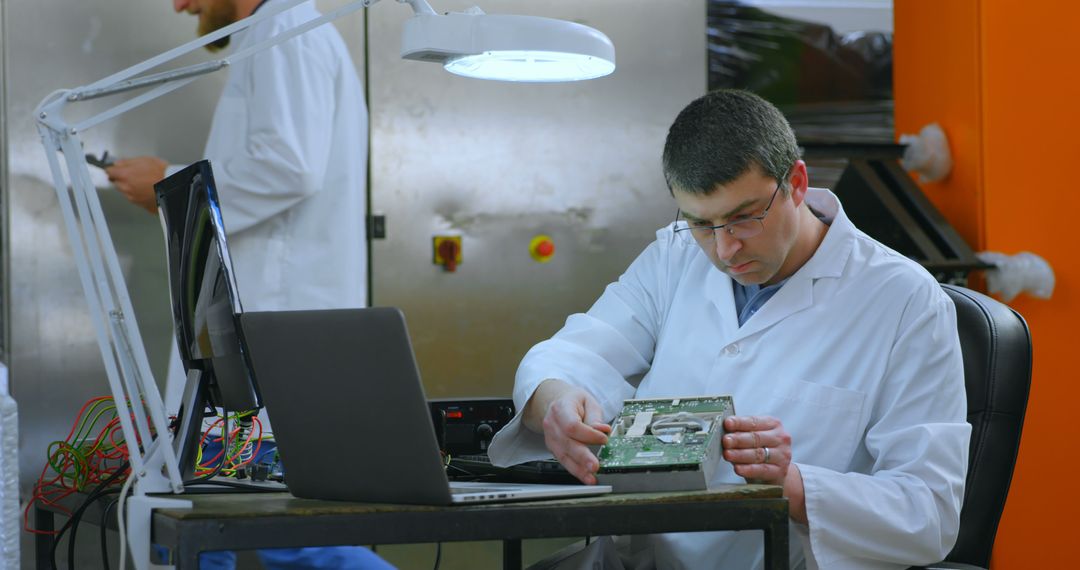 Engineer Examining Circuit Board in Lab Setting with Colleague - Free Images, Stock Photos and Pictures on Pikwizard.com