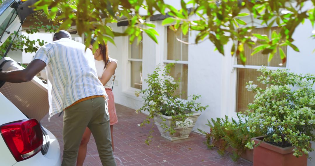 Couple Loading Suitcase into SUV Trunk on Driveway