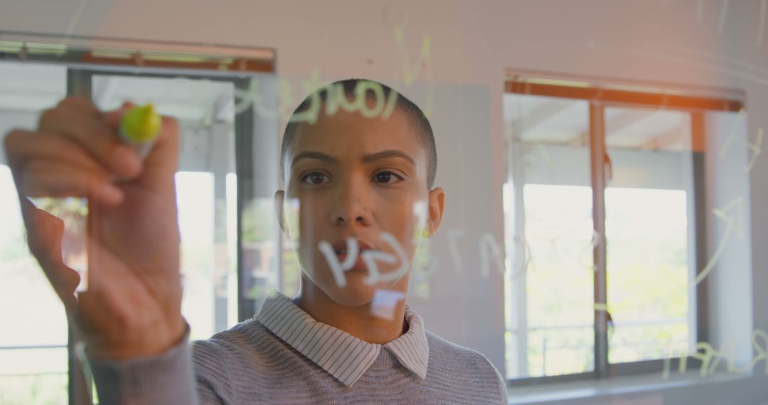 Focused Woman Writing on Glass with Marker in Office Setting - Free Images, Stock Photos and Pictures on Pikwizard.com