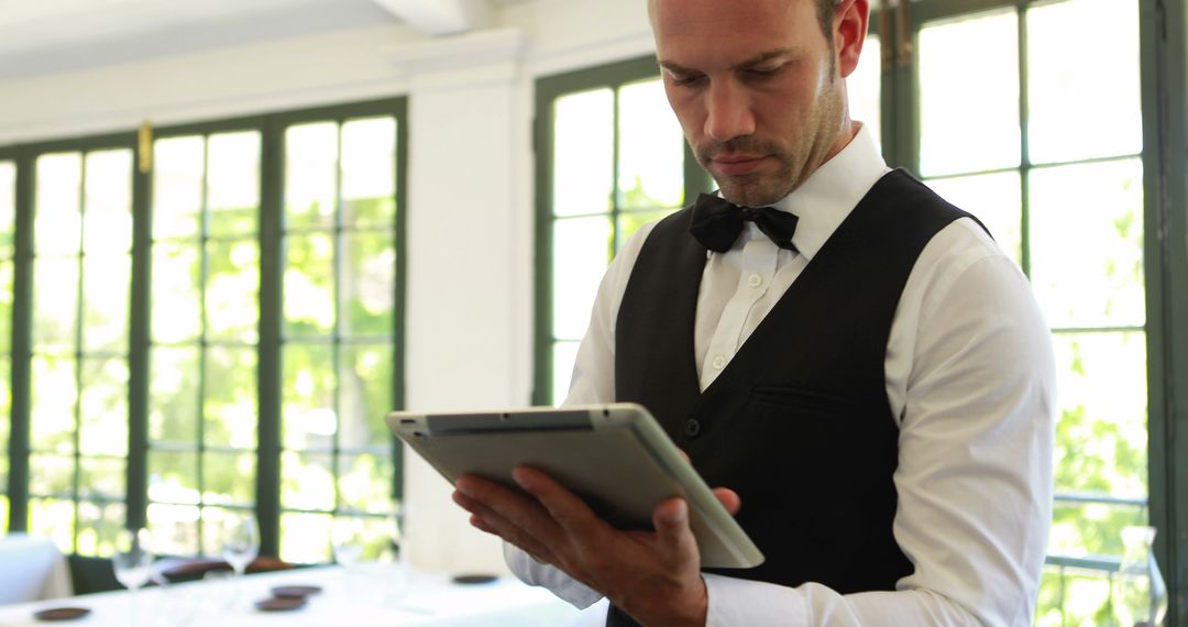 Waiter in Elegant Restaurant Using Tablet for Order Management - Free Images, Stock Photos and Pictures on Pikwizard.com