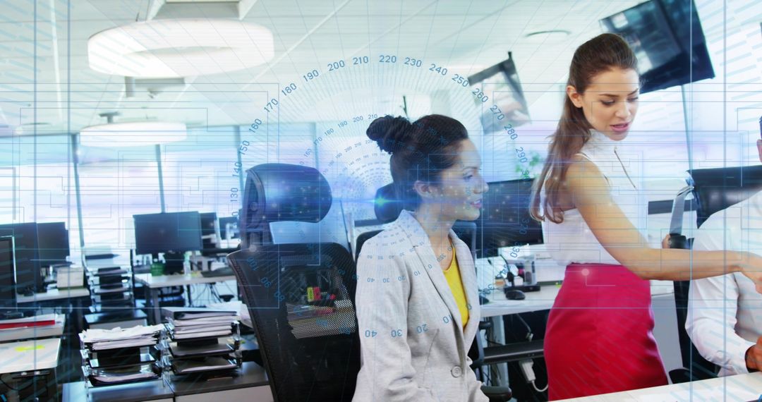 Two Businesswomen Collaborating at Open-Plan Office with Digital HUD Data Analytics Overlay