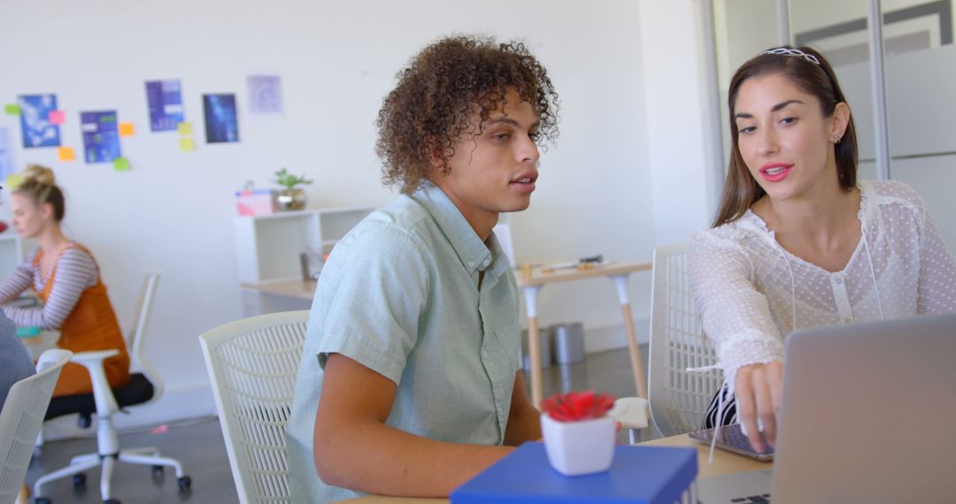 Focused Colleagues Collaborating on Project Using Laptop in Modern Office