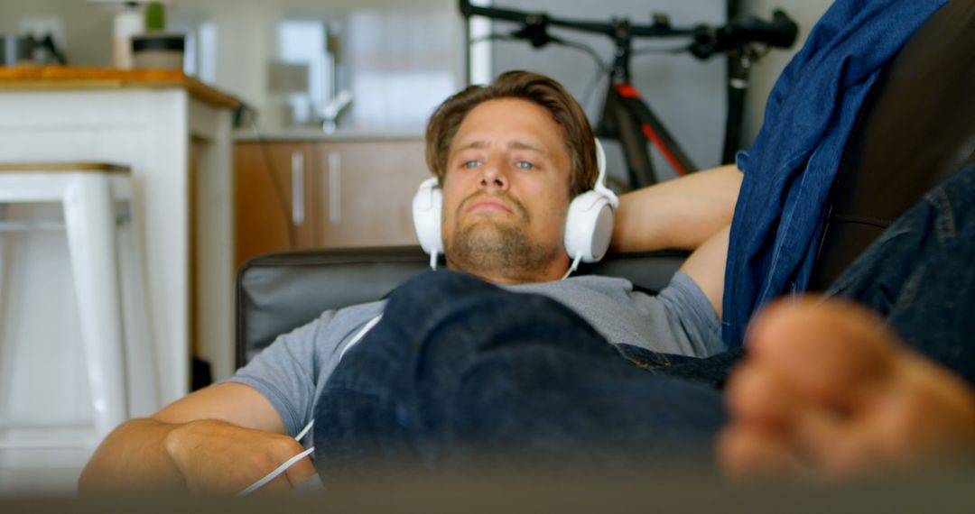 Man Relaxing on Couch with Headphones, Enjoying Leisure Time - Free Images, Stock Photos and Pictures on Pikwizard.com