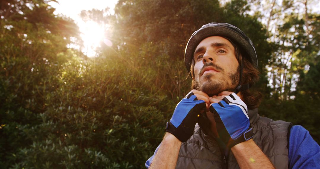 Cyclist Adjusting Helmet in Sunlit Forest - Free Images, Stock Photos and Pictures on Pikwizard.com