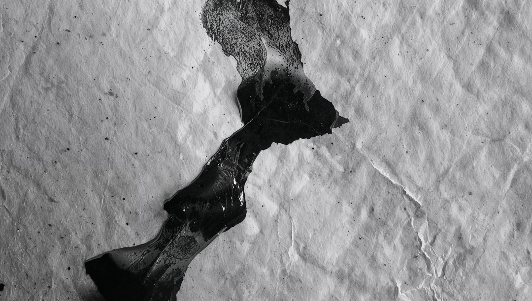 Glossy black ink smear spreading across crumpled paper texture with high contrast