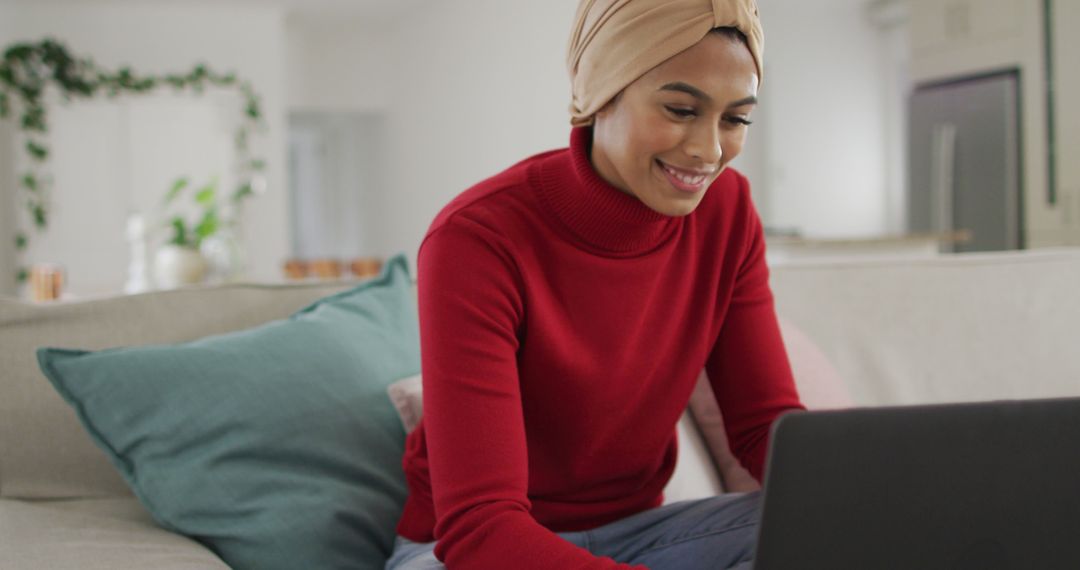 Image of happy biracial woman in hijab sitting on sofa and having image call - Free Images, Stock Photos and Pictures on Pikwizard.com