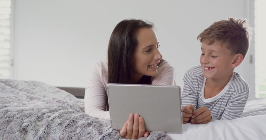 Mother and Son Smiling While Using Digital Tablet in Bedroom - Free Images, Stock Photos and Pictures on Pikwizard.com