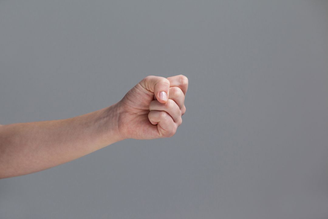 Close-up of Clenched Fist Against Grey Background - Free Images, Stock Photos and Pictures on Pikwizard.com