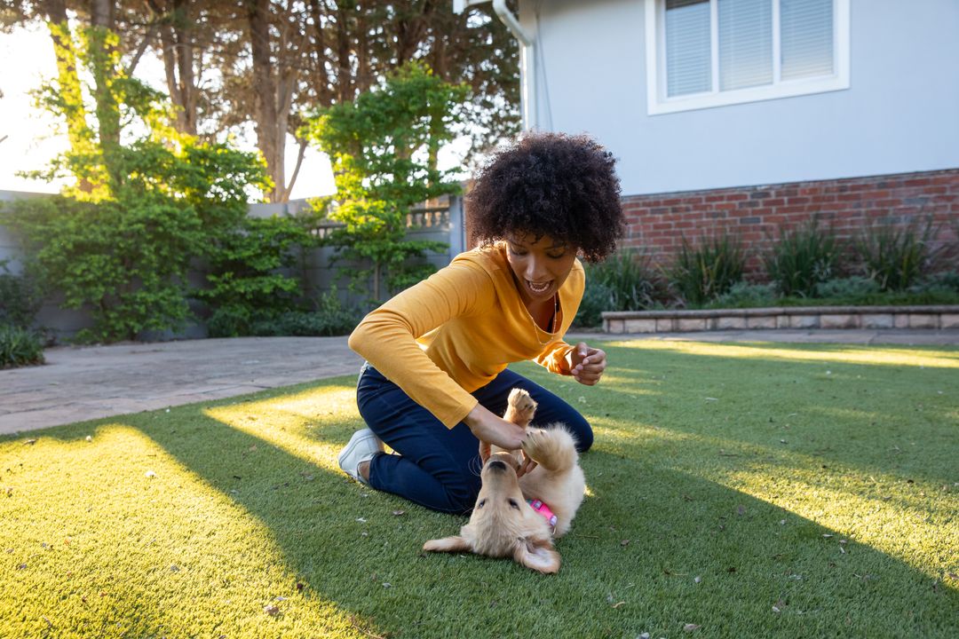 Woman Joyfully Playing with Energetic Puppy in Sunlit Backyard
