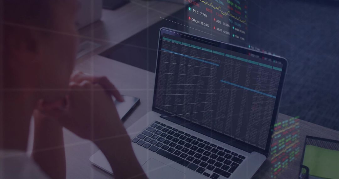 Leaning woman viewing laptop with stock data and charts, tablet beside desk, glass reflections