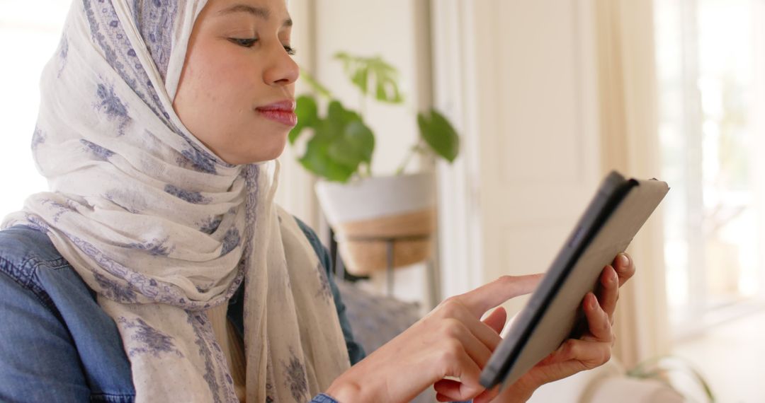 Hijabi Woman Engaged with Tablet at Home - Free Images, Stock Photos and Pictures on Pikwizard.com