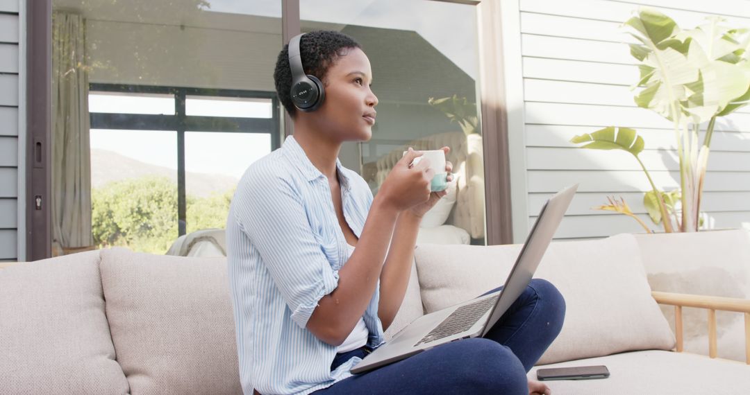 Woman Working Outdoors with Laptop and Headphones While Drinking Coffee - Free Images, Stock Photos and Pictures on Pikwizard.com