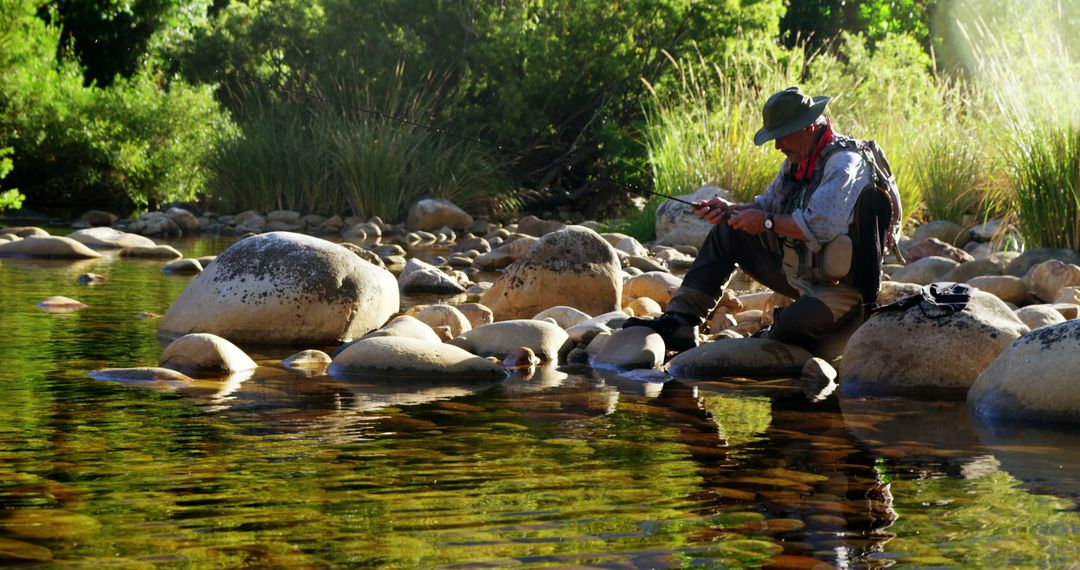 Angler Sitting on Rocks by River in Nature - Free Images, Stock Photos and Pictures on Pikwizard.com