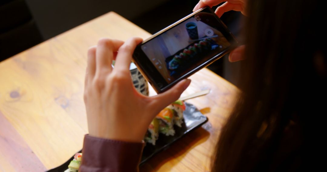 Person taking photo of sushi on wooden table - Free Images, Stock Photos and Pictures on Pikwizard.com