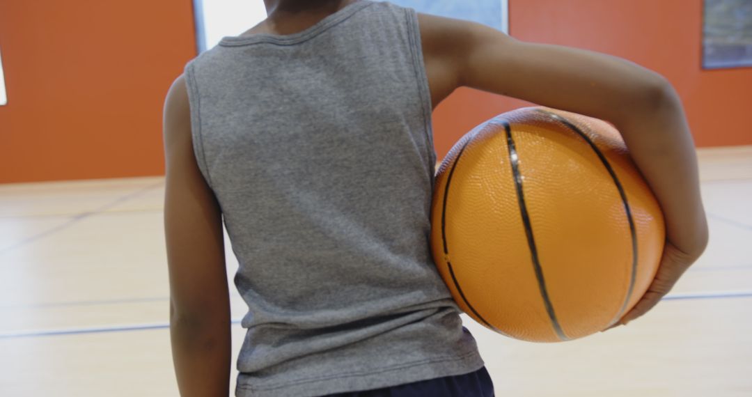 Child Holding Basketball in Gym Preparing for Game