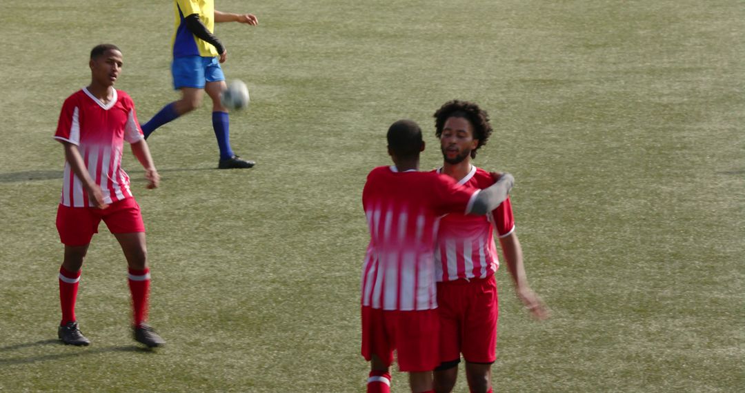 Soccer Players Embracing After Scored Goal on Green Field