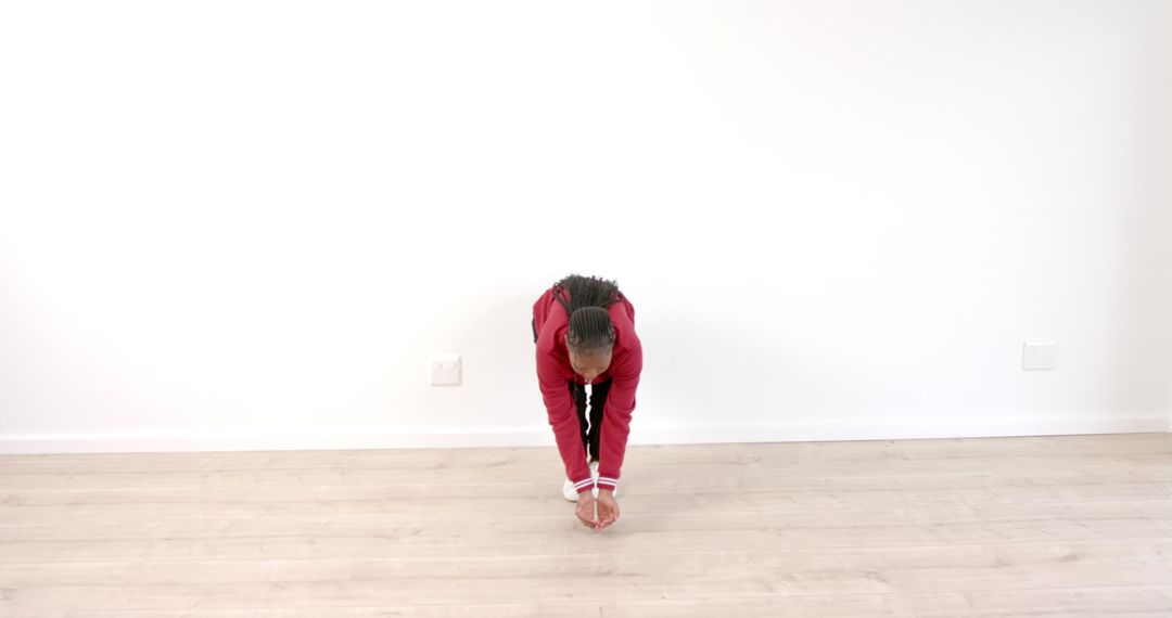 Person in Red Jacket Performing Forward Bend Stretch