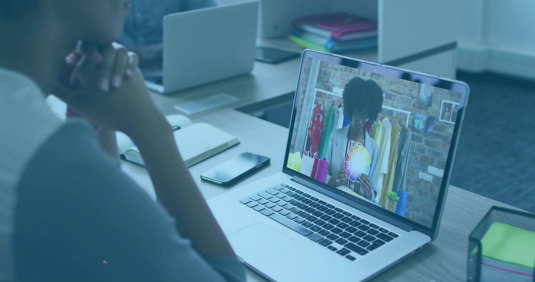 Watching virtual fashion presentation on laptop at coworking desk for remote collaboration