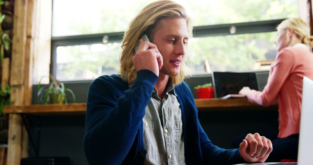 Man With Long Blonde Hair Having Phone Call in Bright Open Office - Free Images, Stock Photos and Pictures on Pikwizard.com