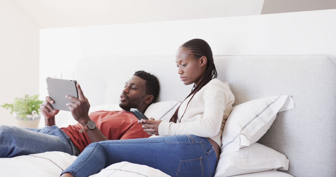 Couple Enjoys Relaxed Time Together Using Gadgets in Bedroom