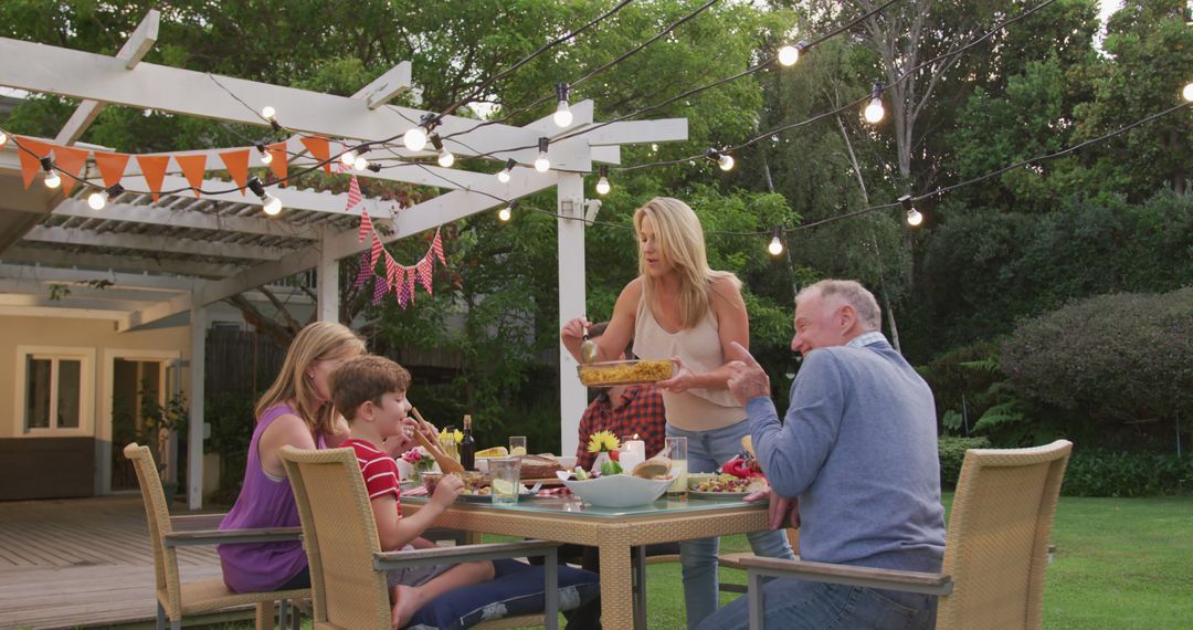 Family Enjoying Outdoor Dinner in Garden with Festive Lights - Free Images, Stock Photos and Pictures on Pikwizard.com