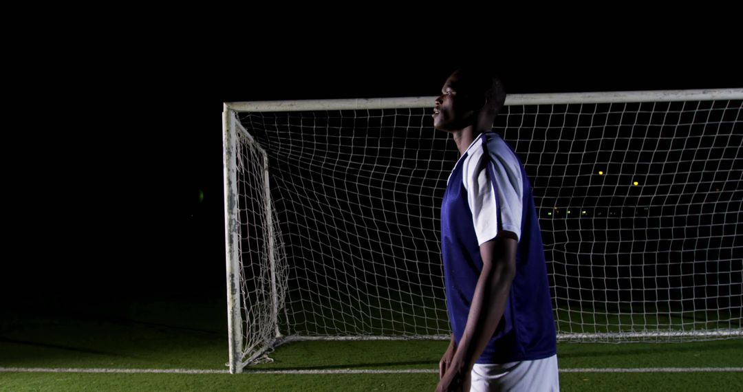 Soccer Player Training Under Night Floodlights on Field