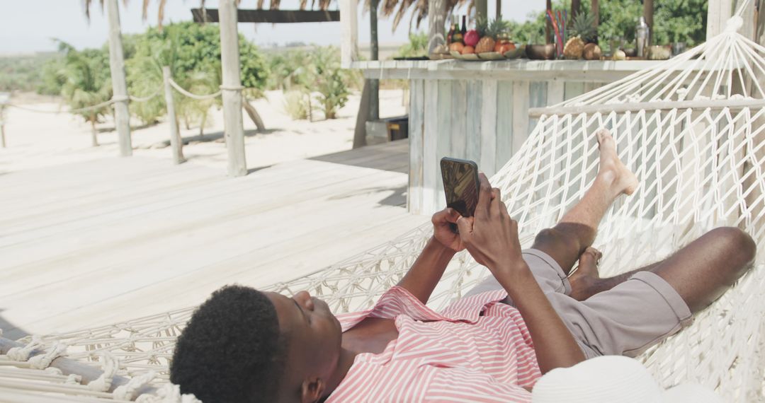 Man Relaxing on Hammock at Beach Resort Using Smartphone - Free Images, Stock Photos and Pictures on Pikwizard.com