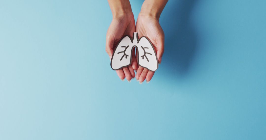 Image of biracial woman holding drawing of lungs on blue background - Free Images, Stock Photos and Pictures on Pikwizard.com