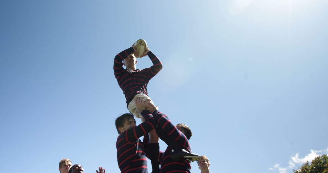 Rugby Players Lifting Teammate for Ball Catch Under Clear Blue Sky - Free Images, Stock Photos and Pictures on Pikwizard.com